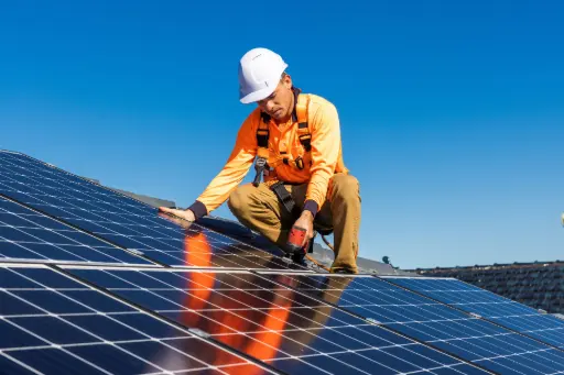  technicien solaire posant des panneaux sur une maison avec harnais de sécurité.